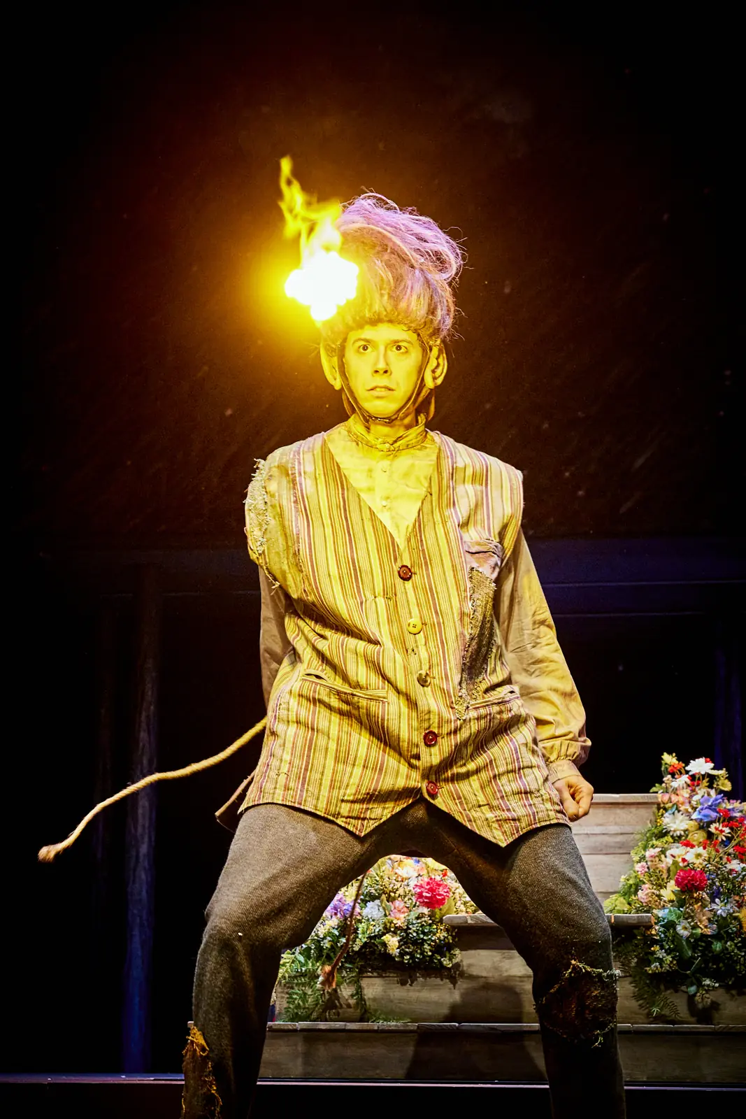 Performer in a golden costume lit by a light source above his head