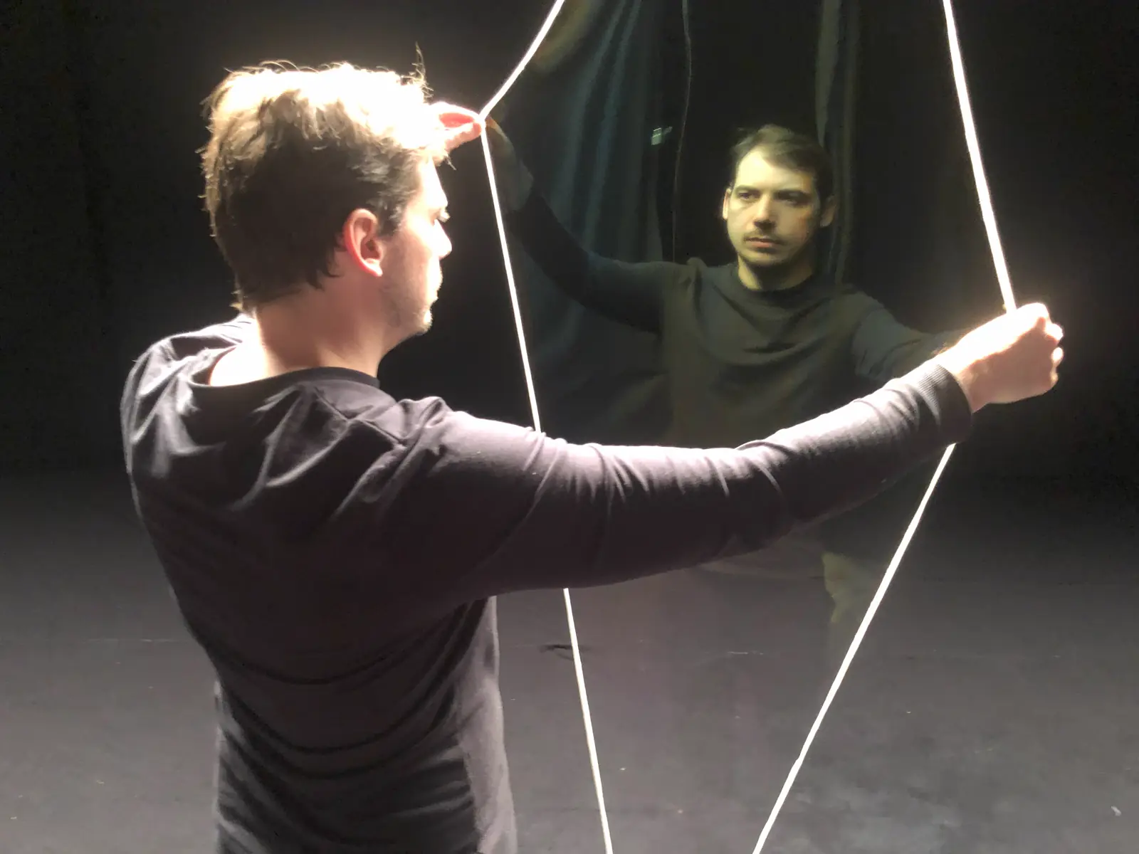 Two technicians rigging illusion wires during a rehearsal