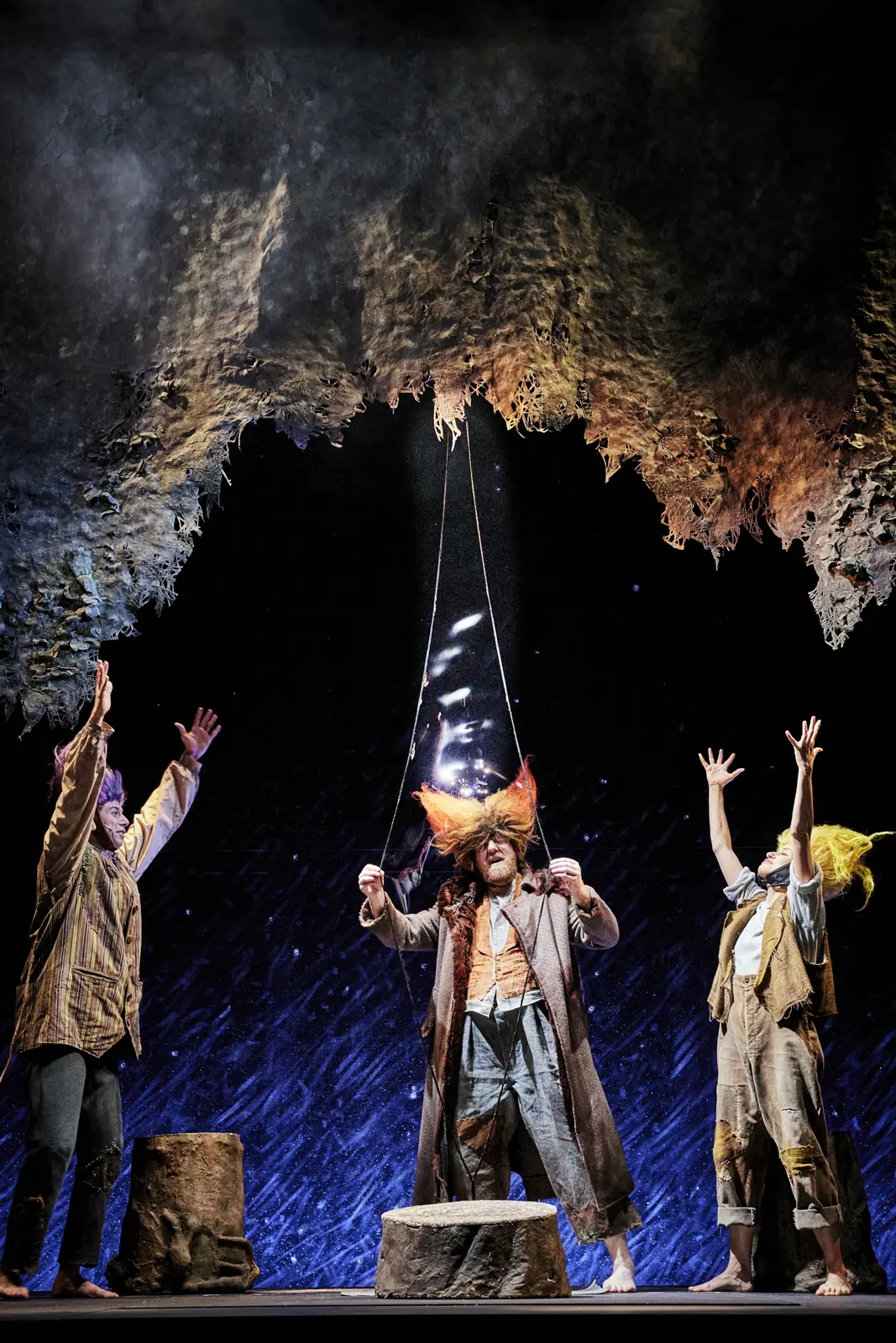 Cave scene under a starry sky, performers with their arms raised